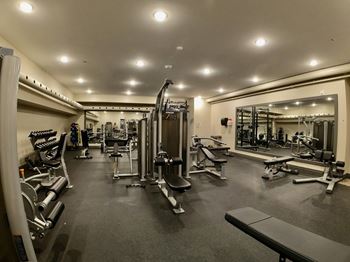 a home gym with a lot of exercise equipment on the floor and a large mirror on the